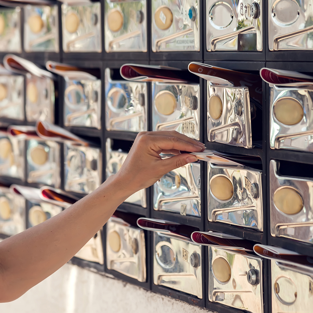Mailboxes with newspaper inside. Woman placing correspondence in a mailbox
